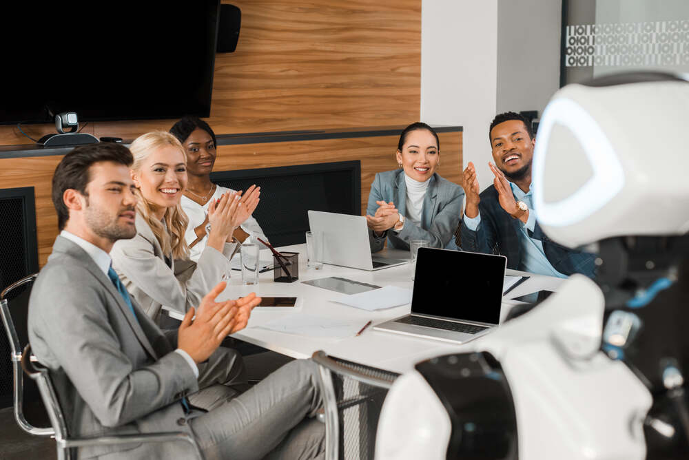 business people applauding while looking at robot in office.